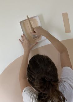 a woman is painting the wall with white paint and she has her hands on top of it