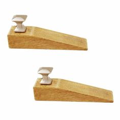 two wooden brackets with white handles on each end and one is holding a pair of wood pegs