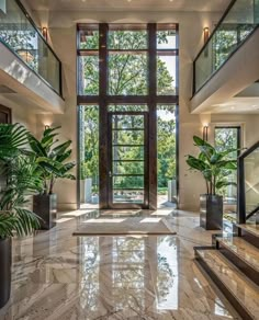 a large foyer with marble flooring and high windows overlooking the trees in the distance