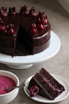 a chocolate cake on a plate with a slice cut out and two bowls of pudding