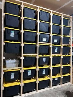 the shelves are filled with black containers and yellow stands in front of each other on wooden pallets