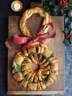 an assortment of pastries on a cutting board next to candles and holly wreaths