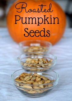 roasted pumpkin seeds in small glass bowls on a table with an orange pumpkin behind them