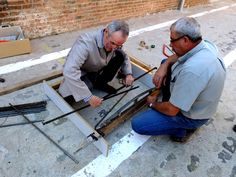 two men working on an unfinished piece of wood