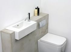 a white toilet sitting next to a sink under a faucet in a bathroom