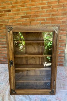 an old wooden bookcase with glass doors on the front and side, sitting against a brick wall