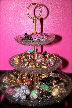 a three tiered tray with lots of jewelry on it