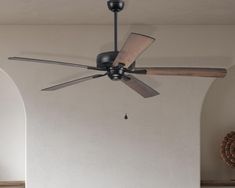 a ceiling fan that is hanging from the ceiling in a room with white walls and arched doorways