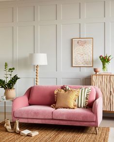 a living room with pink couches and plants in vases on the side table