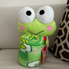 a green stuffed animal sitting on top of a couch