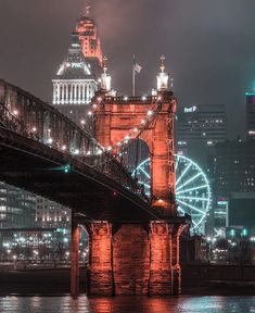 the city skyline is lit up at night, with lights on and ferris wheel in the foreground