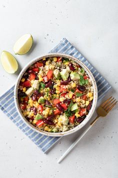 a bowl filled with rice and vegetables next to two slices of lemons on top of a blue towel