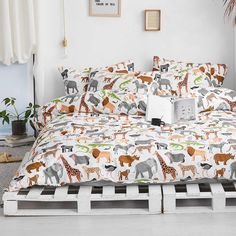 a bed covered in lots of animals on top of a wooden pallet next to a potted plant