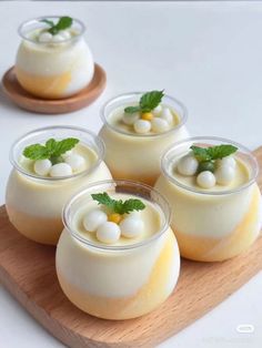 four desserts with white chocolate and mint garnishes on a wooden platter