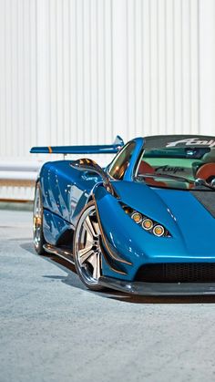 a blue sports car parked in front of a building