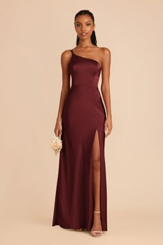 a bridesmaid in a burgundy gown with one side slited, holding a bouquet