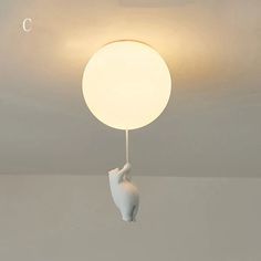 a white lamp hanging from the ceiling with a cat on it's back end