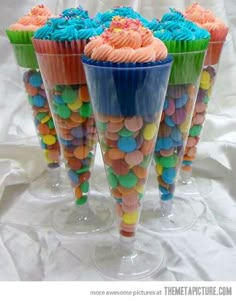 cupcakes with colorful frosting and sprinkles on them are in cups