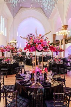 the tables are set with black linens and pink flowers