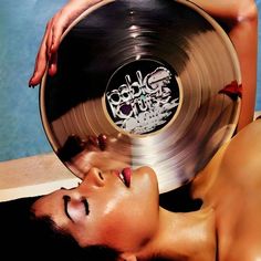 a woman laying on the ground with a record in her hand next to her face