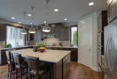 a large kitchen with an island in the middle and lots of lights hanging from the ceiling