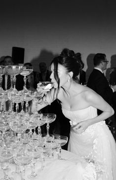 a woman standing next to a table filled with wine glasses