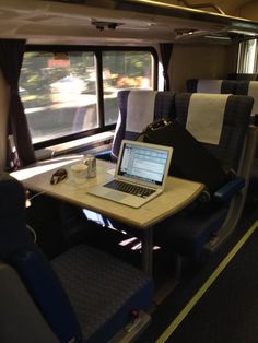 an open laptop computer sitting on top of a wooden table next to a window filled with curtains