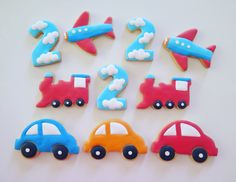 decorated cookies in the shape of cars, planes and numbers on a white table top