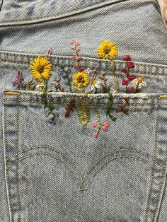 the back pocket of a pair of jeans with flowers embroidered on it