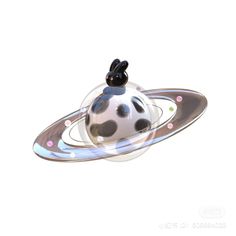 a black and white cat sitting on top of a ball in the shape of a saturn