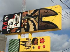 two large billboards with paintings on them against a blue sky and white clouds in the background