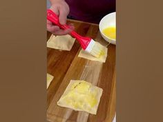 a person using a red brush to spread butter on crackers