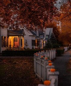 pumpkins are lined up along the fence in front of a house at night time