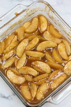 apple slices are sitting in a glass casserole dish on a marble countertop