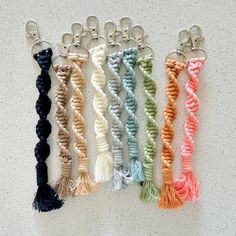 five different colors of key chains with tassels hanging from each one's side