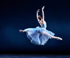 a ballerina is in the air with her arms stretched out and legs spread wide