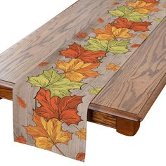 a wooden table topped with an autumn leaf table runner next to a wood dining room table