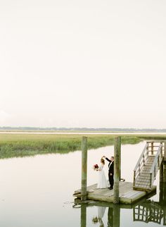 a bride and groom standing on a dock