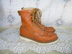 Distressed orange leather boots by The Gorilla Shoe. These have lightweight foam-like ripple soles. They lace up the front with yellow and brown laces. They have a good amount of wear such as scuffs, scratches in the leather, mostly on the toe, creasing, and green paint here and there, including on the soles and shoe laces. The white stitching is darkened in many places. The white piping at the top of the boots has cracking in it (see photos). There are a few red marks in the leather. Overall these do have wear, but are a nice design and still have life in them.  The inside soles say that these have a genuine goodyear welt and were made in India. There's a funny tag on the inside of the tongue showing a gorilla with the words "brutally strong." The soles are oil resistant.  Size marked: Me Shoes Boots Combat, Red Marks, 90s Grunge, Mens Shoes Boots, Orange Leather, Green Paint, Goodyear Welt, Yellow And Brown, Work Boots