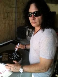 a man sitting at a table with a record in his hand and writing on it