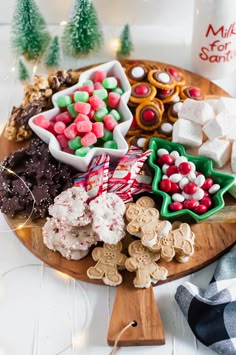 a wooden platter filled with assorted cookies and marshmallows