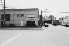 a black and white photo of an empty street with cars parked in front of the building