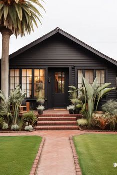 a black house with some plants in the front yard and steps leading up to it