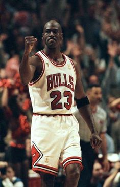 a basketball player holding his fist up in the air while standing next to an audience