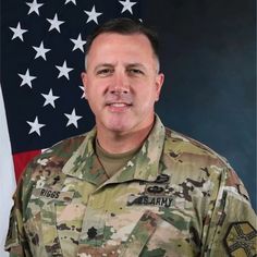 a man in uniform standing next to an american flag