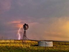 a windmill in the middle of a field with lightning