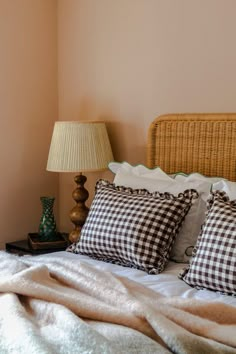 a bed with two pillows on top of it and a lamp next to the headboard