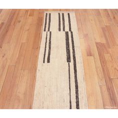 a white and black runner rug on the floor with wooden floors in front of it