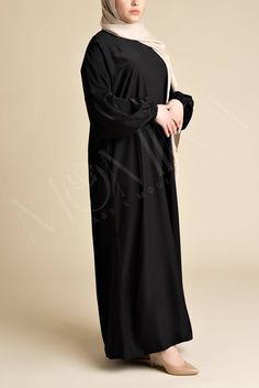 Embody the essence of modesty with our Classic Luxe Relaxed Abaya - Arwaa. A timeless black abaya that falls beautifully, creating a relaxed, a-line fit that ensures a graceful appearance. Made from the finest nida fabric, Arwaa offers a relaxed, flowy silhouette that drapes effortlessly, creating a look of sophisticated ease. This abaya blends simplicity with functionality, offering side pockets for your belongings, elastic cuff sleeves for ease during wudhu, and a back zip closure for a perfec Modest Black Khimar, Modest Black Abaya With Long Sleeves, Modest Black Long Sleeve Abaya, Modest Long Sleeve Black Abaya, Modest Long Sleeve Black Khimar, Modest Black Long Sleeve Khimar, Long Sleeve Black Khimar For Eid, Black Long Sleeve Khimar For Eid, Elegant Black Abaya With Modesty Panel