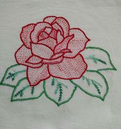 a rose embroidered onto a white cloth with green and red stitching on the edges